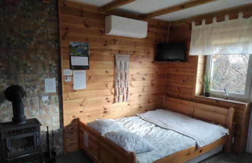 a bed in a wooden room with a stove at Domek pod Kamieńcem in Odrzykoń