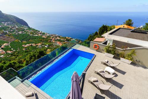 a swimming pool on top of a house with the ocean at Villa António in Arco da Calheta