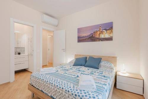 a white bedroom with a bed with blue pillows at La Casa di Biancaneve in Recco