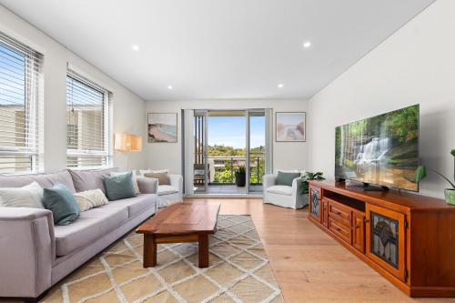 a living room with a couch and a flat screen tv at Seaside Retreat with Parking and Balcony in Newport