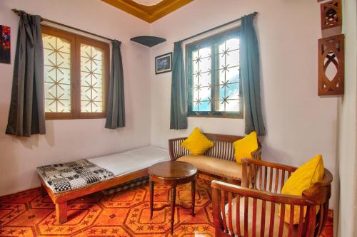 a room with a couch and a table and two windows at Anjuna House With Ocean View in Anjuna