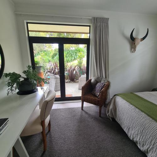 a bedroom with a bed and a desk and a window at Sandspit Hideaway in Sandspit