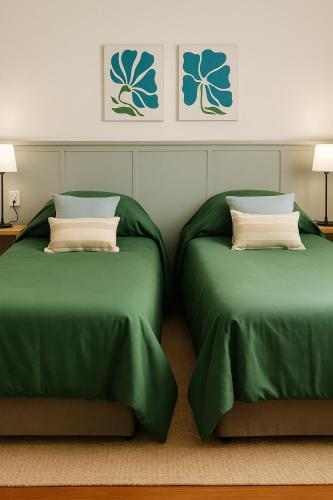 two beds in a room with green sheets and pillows at Madaro House in San Antonio de Arredondo