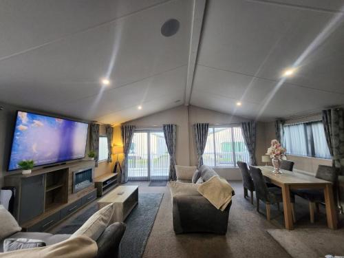 a living room with a large tv and a table at Hot tub lodge grange leisure park Mablethorpe in Mablethorpe