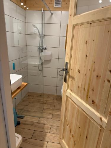een badkamer met een douche, een wastafel en een deur bij Małe Schronisko in Szczyrk