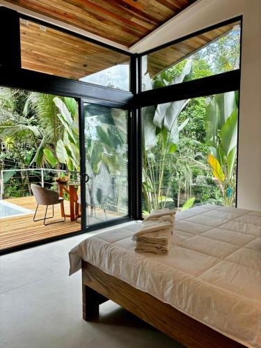a bedroom with a bed and a large window at Exclusive Rainforest Villas in Tapantí