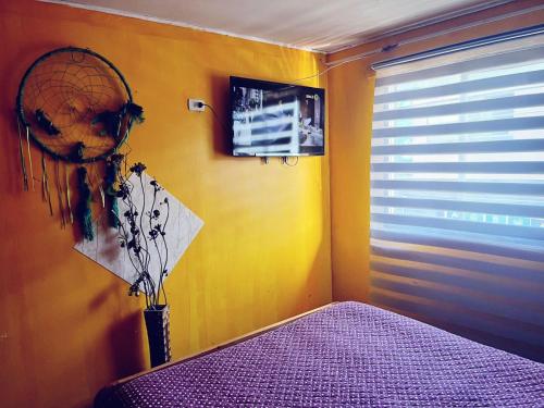 a bedroom with a yellow wall with a fan and a bed at Hotel del valle in Melipilla