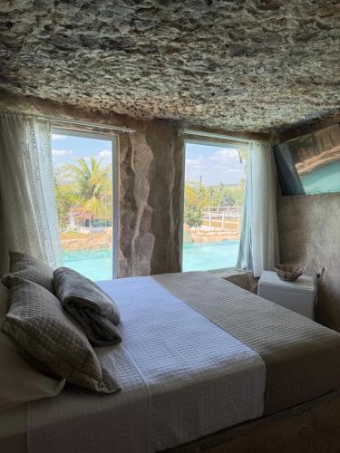 a bedroom with a bed and a large window at Rancho Navarro - Caverna in Pôrto de Pedras