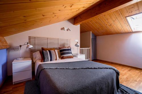 1 dormitorio con cama grande y techo de madera en Paramita Adosado con Jardin, en Villanúa