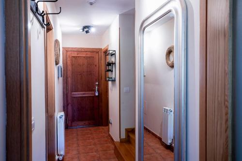 pasillo con puerta de madera y pasillo con espejo en Paramita Adosado con Jardin, en Villanúa