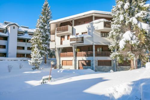 un edificio nella neve con una panchina davanti di Snow White - Happy Rentals a Bardonecchia