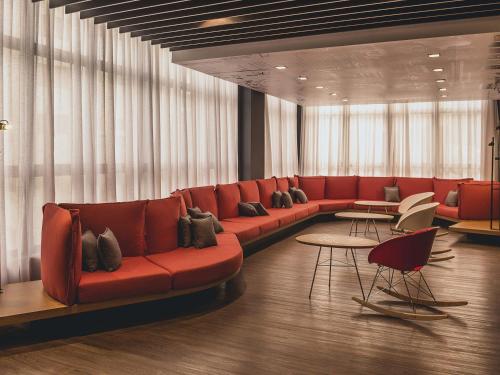 a living room with a red couch and tables at ibis Carlos Barbosa in Carlos Barbosa