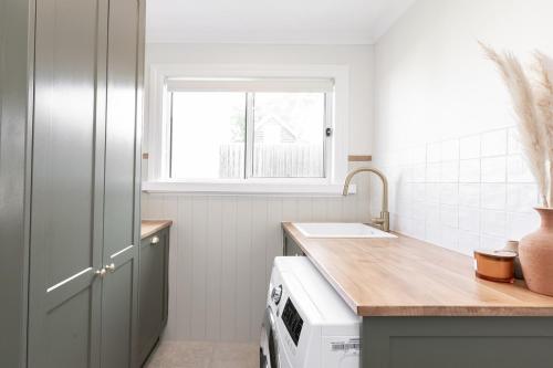 a white kitchen with a sink and a window at Koroit Street Cottage in Warrnambool
