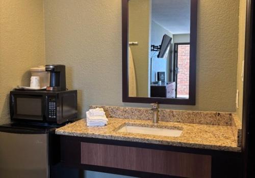 a bathroom with a sink and a microwave and a mirror at Twin Lakes Inn & RV Park in Stigler