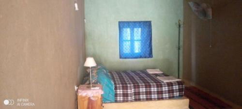 a small bedroom with a bed and a window at DAR MIRA DUNES Hassilabiad-Merzouga in Hassilabied