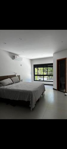 a bedroom with a large bed and a large window at Apartamento aconchegante e moderno próximo do aeroporto e ao centro in Porto Seguro