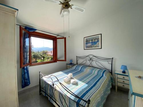 a bedroom with a bed with a ceiling fan and a window at Villa Vittoria in San Teodoro
