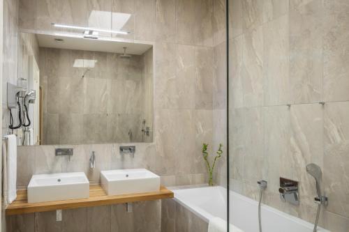 uma casa de banho com 2 lavatórios, uma banheira e um espelho. em Masná 19 - Old Town Residence em Praga