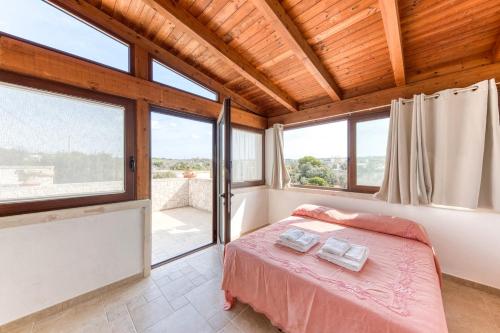 カストリニャーノ・デル・カーポにあるVilla Liscedde Leucaのベッドと大きな窓のある寝室