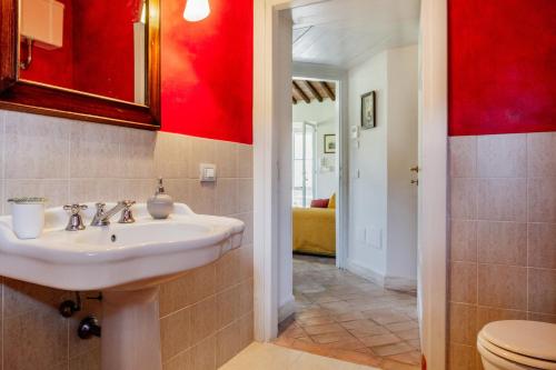 La salle de bains est pourvue d'un lavabo et d'un mur rouge. dans l'établissement Tenuta Valle Buia, à Orbetello