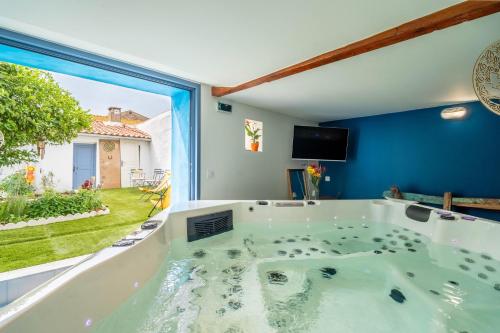 a bath tub in a room with a large window at Gîte indépendant l'Orchidée in Lespignan