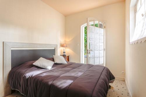 a bedroom with a large bed with a large window at Longère proche plage et forêt in Saint-Trojan-les-Bains