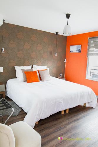 a bedroom with a large white bed with orange walls at L'Hostellerie d'Acquigny in Acquigny