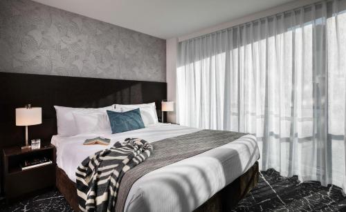 a bedroom with a large bed with a large window at Rydges Wellington in Wellington