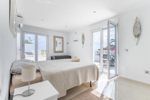 a white bedroom with a bed and a balcony at Modern villa with great location in Ciudad Quesada