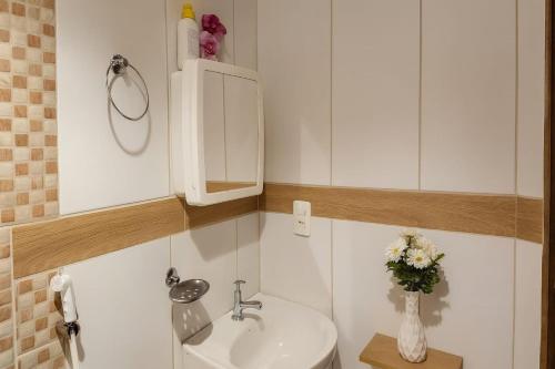 a bathroom with a sink and a vase of flowers at Casa Maré Alta – Piscina e Sossego em Tabuba in Santa Luzia