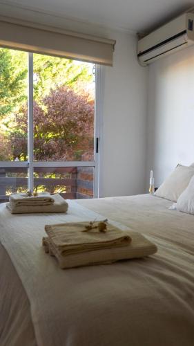 a white bed with two wooden items on it at Verde Lillo in Necochea