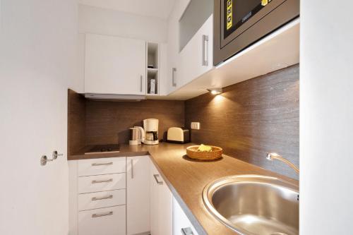 a kitchen with white cabinets and a sink at Birkethof Fernblick in Grimoldsried