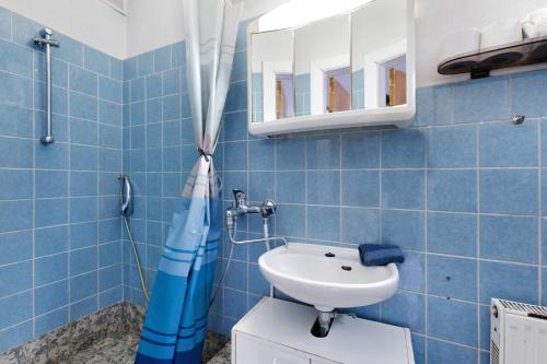 a blue tiled bathroom with a sink and a mirror at Hamdorf, Hauptstraße Unten in Hamdorf