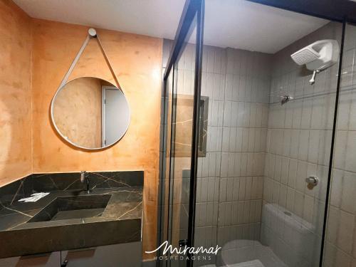 een badkamer met douche, wastafel en spiegel bij Ozean Home Service - Jardim Oceania in Tambaú