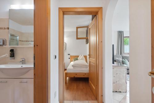 łazienka z umywalką oraz pokój z łóżkiem w obiekcie Prackfolerhof w mieście Fie allo Sciliar