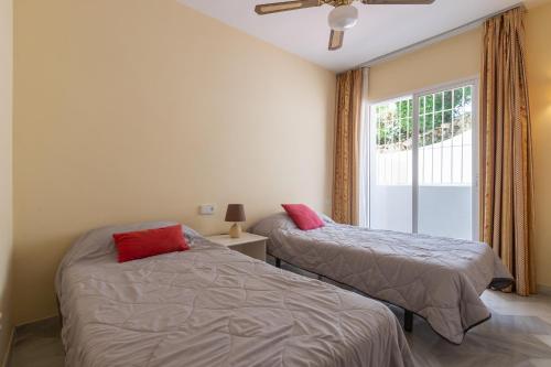 two beds in a room with a window at Lovely 2 bed apt overlooking golf in Mijas Costa
