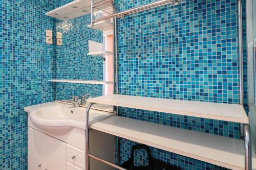 La salle de bains est pourvue de carrelage bleu, d'un lavabo et d'un miroir. dans l'établissement Maison Plouha proche plage, à Plouha