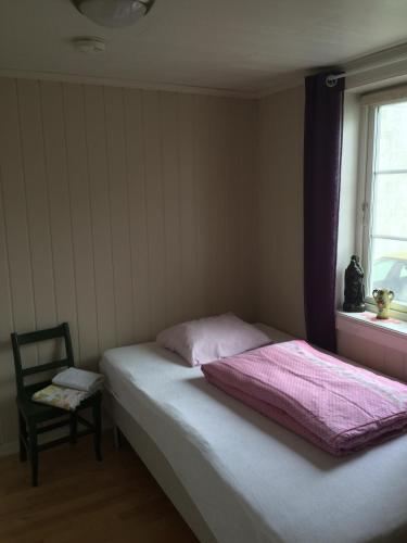 a bedroom with a bed and a chair and a window at Mandal Privat Rom og husutleie in Mandal
