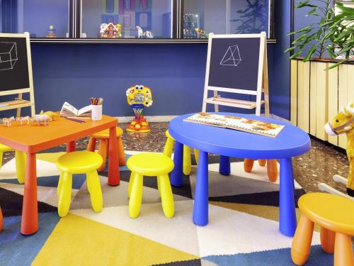 a room with brightly colored tables and chairs at ibis styles Trani in Trani