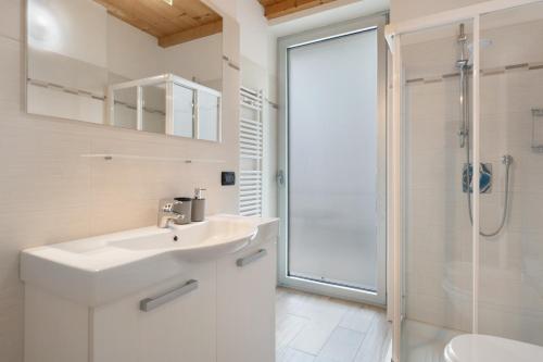 a white bathroom with a sink and a shower at Appartamento Jubilant in Comano Terme