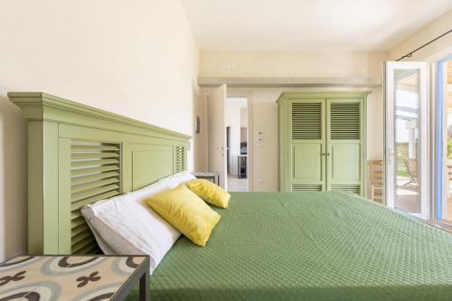 Elegante villa a Otranto في أليميني: غرفة نوم بسرير اخضر كبير مع مخدات صفراء