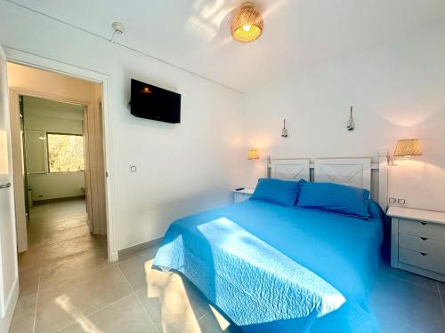 sypialnia z niebieskim łóżkiem i telewizorem w obiekcie Addaia w mieście Port d'Addaia