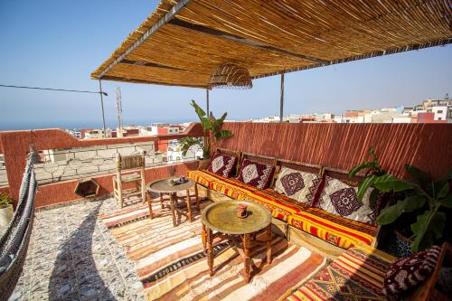 a couch on a balcony with tables and chairs at Wave Stay Hostel - Sea View in Agadir
