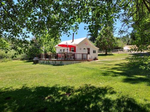 a house with a red roof on a grass field at Meadow Creek Cabin in Camino