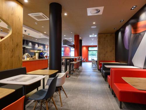 a restaurant with red and black tables and chairs at ibis Regensburg Zentrum in Regensburg