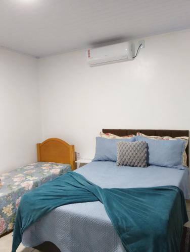 a bedroom with a bed with a blue comforter at Cantinho da Ju in Osório