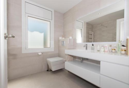 ein Badezimmer mit Waschbecken, Toilette und Spiegel in der Unterkunft Villa Berganti in Canet de Mar