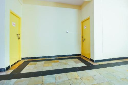 a hallway with two yellow doors and a tiled floor at Hotel O Sai Residency Near SR Nagar metro station in Hyderabad