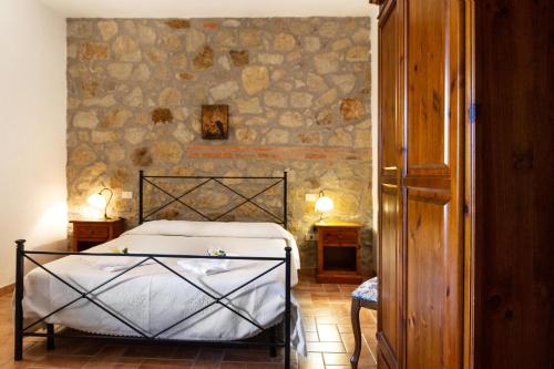 a bedroom with a bed and a stone wall at Capracotta - Luna in Montemassi