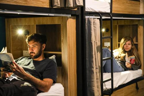 a man sitting in a bed reading a book at Crashpalace Napier in Napier